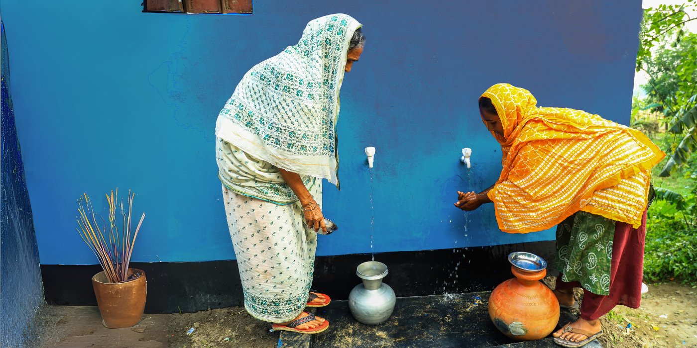 Two women tap fresh, clean water at a new well