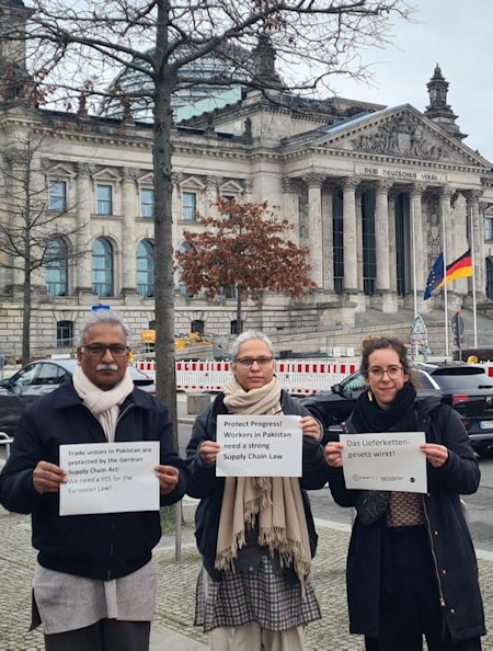 Nasir Mansoor (NTUF), Zehra Khan (HBWWF) und Sina Marx (FEMNET) protestieren für das Lieferkettengesetz vor dem Reichstagsgebäude in Berlin, Januar 2024. 