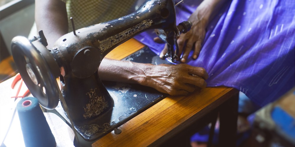 Women's hands on sewing machine blue fabric