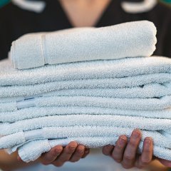 Hauskeeperin hält frische, weiße, gefaltete Handtücher in den Händen